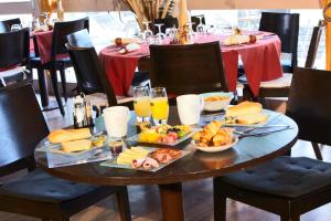 a table with plates of food and glasses of orange juice at Kyriad Beauvais Sud in Beauvais +11 photos