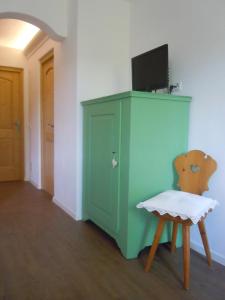 a room with a green cabinet and a chair at Feldererhof in Siusi