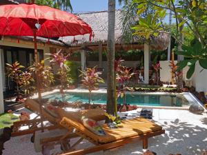 a resort with a pool with a red umbrella and a bench at Hakuna Matata Bali Villas in Uluwatu