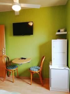 ピルナにあるPrivatzimmer mit Aussichtの緑の壁の客室で、テーブルと椅子2脚が備わります。