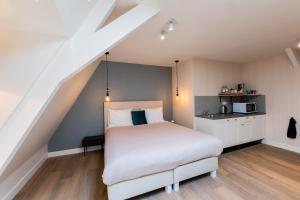 a bedroom with a white bed and a kitchen at Stadsvilla Mout Rotterdam-Schiedam in Schiedam