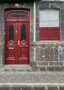 a red door and two windows on a building at CC Guest House - "Ao Mercado" in Ponta Delgada