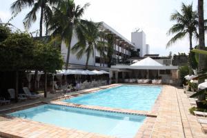 a large swimming pool next to a hotel with palm trees at Ubatuba Palace Hotel in Ubatuba