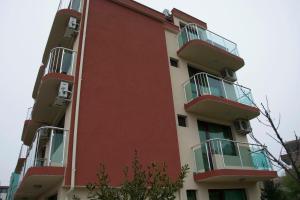 a red building with balconies on the side of it at Stedy Guest House in Chernomorets