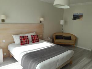 a bedroom with a large bed and a chair at Hôtel Ker-Noyal Quiberon Plage in Quiberon