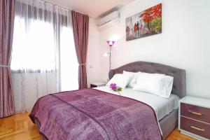 a bedroom with a large bed with a purple blanket at Apartment Anatolia - Mina in Becici