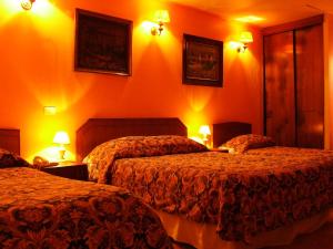 two beds in a hotel room with orange walls at Hotel Balia Casino in Viña del Mar