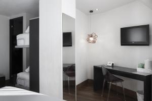 a bedroom with a desk and a tv on the wall at Petit Palace Plaza Mayor in Madrid