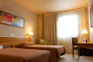 a hotel room with two beds and a television at Expo Hotel Valencia in Valencia