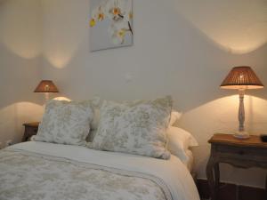 a bedroom with a bed with pillows and two lamps at Mil Reis in Vila Nova de Milfontes