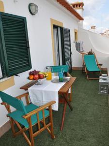 a patio with a table with chairs and fruit on it at Mil Reis in Vila Nova de Milfontes