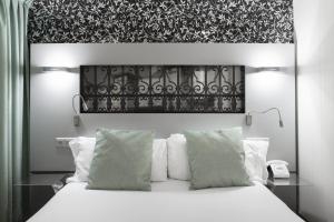 a bedroom with a white bed with a black and white headboard at Petit Palace Plaza Mayor in Madrid