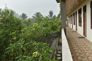 a walkway next to a building with flowers and trees at PIAS POPPIES HOTEL in Rantepao +8 photos