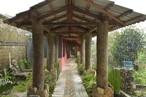 een houten pergola over een loopbrug in een tuin bij PIAS POPPIES HOTEL in Rantepao