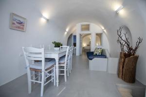 Un comedor blanco con una mesa y sillas blancas. en Santo Blue Horizon Blue domes view, en Oia
