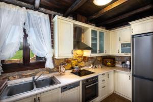a kitchen with white cabinets and a sink and a refrigerator at Sithonian Blue Royal Villa in Nikiti