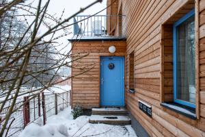 een houten huis met een blauwe deur in de sneeuw bij Chata Terezie in Červená Voda