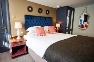 a bedroom with a large bed with a blue headboard at The Fleece at Cirencester in Cirencester