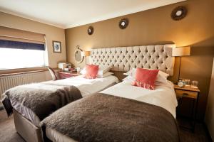 two beds in a hotel room with red pillows at The Fleece at Cirencester in Cirencester
