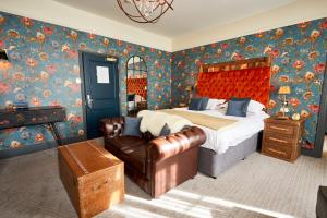 a bedroom with a bed and a leather chair at The Fleece at Cirencester in Cirencester