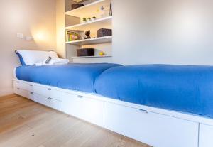 - une chambre avec un grand lit bleu et des étagères blanches dans l'établissement Greeter-Le Petit Versailles, à Versailles