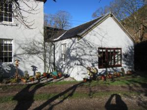 a small white house with a window and some plants at balcraggie in Glenelg