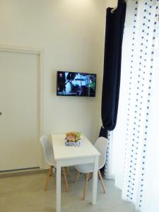 een witte tafel en stoelen met een tv aan de muur bij B&B Lemon Flats in Napels +48 foto's