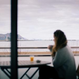 Eine Frau, die an einem Tisch mit einer Tasse Kaffee sitzt. in der Unterkunft Petit Palace Tamarises in Getxo