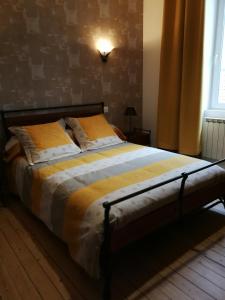 a bedroom with a large bed with yellow and white sheets at Le Dauphin in Chabeuil