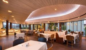 a restaurant with white tables and chairs and windows at Kemer Country Hotel İstanbul in Istanbul