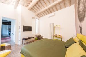 a bedroom with a green bed and a tv at Fonte Gaia Experience in Siena