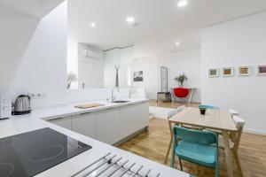 eine Küche mit weißen Arbeitsflächen sowie einem Tisch und Stühlen in der Unterkunft Loft Candela in Sevilla