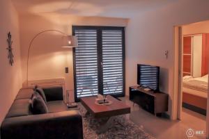 a living room with a couch and a table and a television at Bluestone Boarding Apartments in Düsseldorf