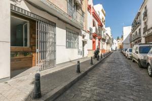 una calle adoquinada con coches estacionados al lado de los edificios en Loft Candela, en Sevilla