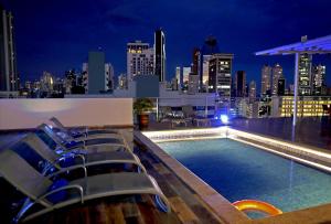 basen na dachu z krzesłami i panoramą miasta w nocy w obiekcie Victoria Hotel and Suites Panama w Panamie