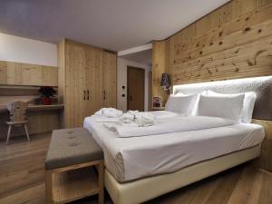 
a hotel room with a bed, chair, and nightstand at Hotel Bertelli in Madonna di Campiglio
