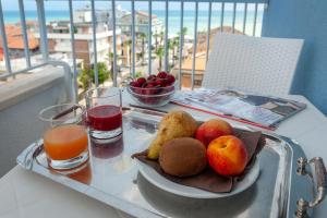 un vassoio di frutta e succhi su un tavolo sul balcone di Hotel Mondial a Porto Recanati