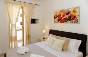 阿爾蓋羅的住宿－阿爾奇拉公寓，卧室配有一张床,墙上挂有绘画作品