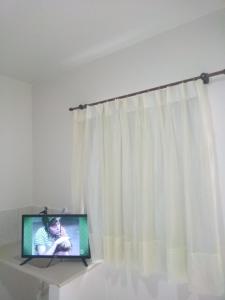 un televisor sentado en una mesa junto a una cortina en Hostel Pigally en Goiânia