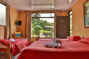 a bedroom with two beds with red sheets and a window at Cabinas Eddy B&B in Monteverde Costa Rica
