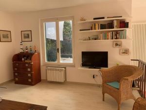 ein Wohnzimmer mit einem TV, einem Stuhl und einem Fenster in der Unterkunft La Cicala, Tellaro in Tellaro