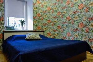 uma cama azul com uma almofada num quarto com papel de parede floral em Гостевой Дом "Bravo" на Казанской em São Petersburgo