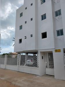 a white building with a gate in front of it at Apartamento com vista para o mar in Jacumã