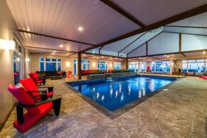 a pool in a house with red chairs at Auberge de la Pointe in Rivière-du-Loup