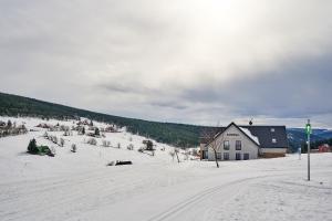 豪洛尼馬拉烏巴的住宿－Apartmán Barborka 07 Horní Malá Úpa，一座白雪覆盖的山丘,远处有一座房子