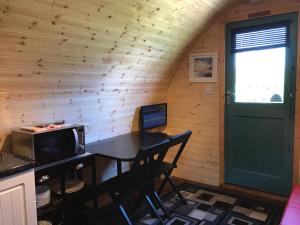 a room with a desk with a television and a door at Spinning Wheel Pod in Dunvegan