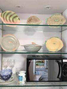 a shelf with bowls and plates and a tv at The Ceramic House in Brighton & Hove