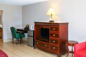 a room with a desk and a dresser with a lamp on top at Toledo Town Inn in Many