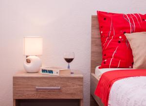 a bed with a red pillow and a glass of wine at Nadalina Apartment in Kastel Stari