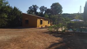 a small yellow building with an umbrella in a yard at EL REFUGIO DE POPEA in Santa María de Trassierra